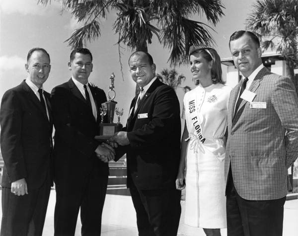 Florida Jaycees president Frank Foster presenting a trophy to an unidentified man during a state convention ceremony in Sarasota.
